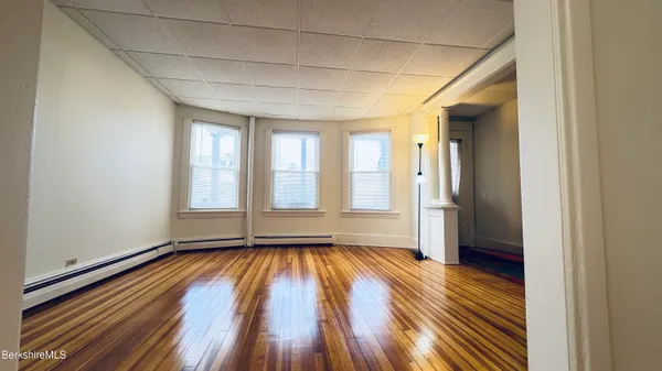 a view of empty room with wooden floor and fan