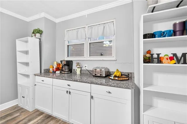 a kitchen with stainless steel appliances granite countertop a refrigerator a oven and white cabinets with wooden floor