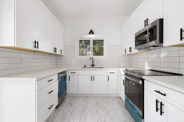 a kitchen with white cabinets stainless steel appliances and sink