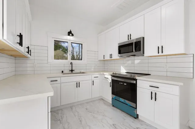 a kitchen with stainless steel appliances white cabinets a sink and a stove