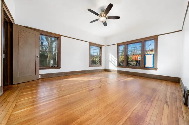 a view of an empty room with a window and wooden floor