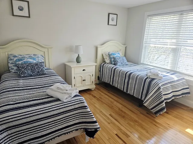 a bedroom with two beds and wooden floor