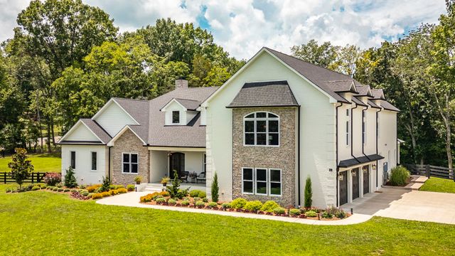 an aerial view of a house with swimming pool and large trees