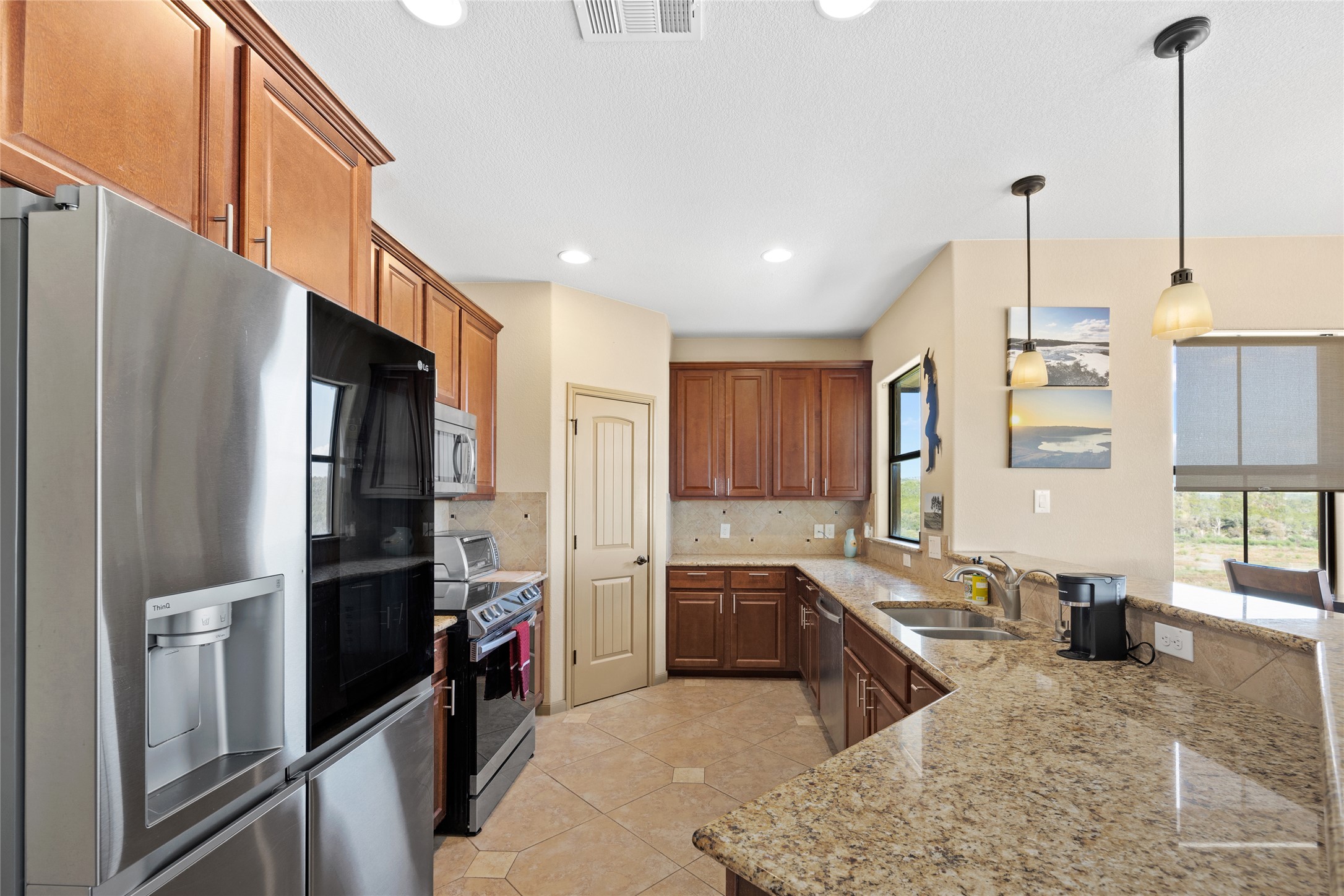 1690 Hickory Creek Road Marble Falls, TX 78654 - Photo 7 of 25 Kitchen featuring appliances with stainless steel finishes, pendant lighting, light tile patterned floors, a peninsula, and backsplash