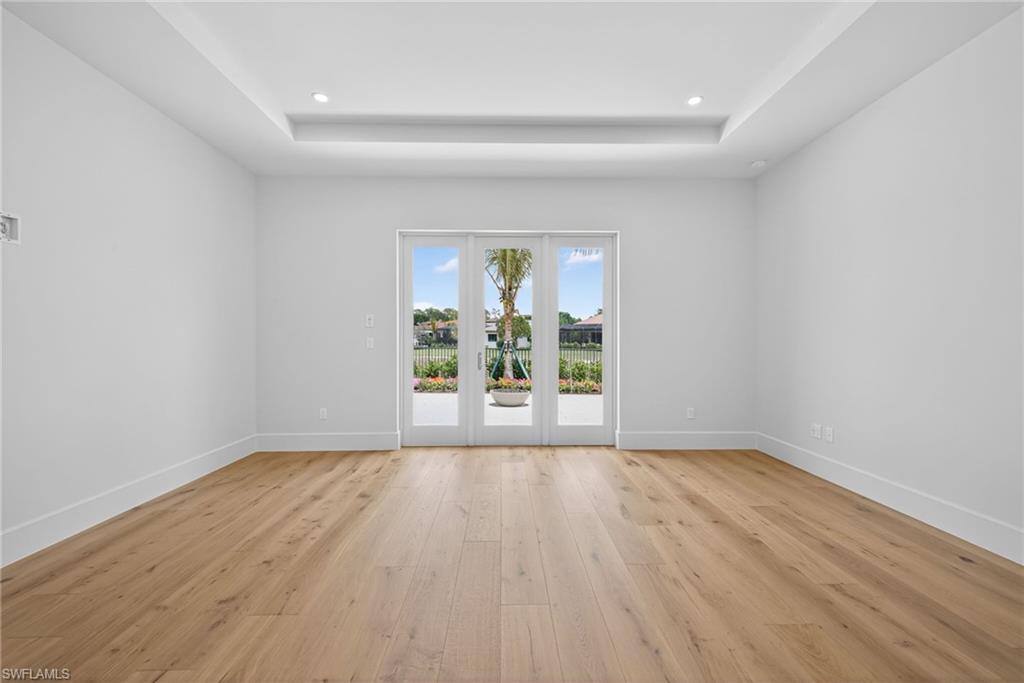 16736 Lucarno Way Naples, FL 34110 - Photo 15 of 49 Master bedroom with lots of natural lighting, wood flooring, a tray ceiling, and recessed lighting