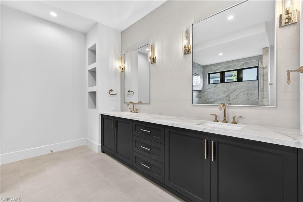 16736 Lucarno Way Naples, FL 34110 - Photo 17 of 49 Master bathroom with double vanity, built in features, recessed lighting, and a marble finish shower