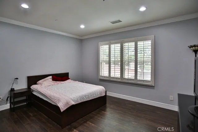 a spacious bedroom with a bed and wooden floor
