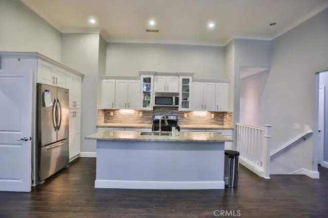 a kitchen with kitchen island a counter top space a sink stainless steel appliances and cabinets