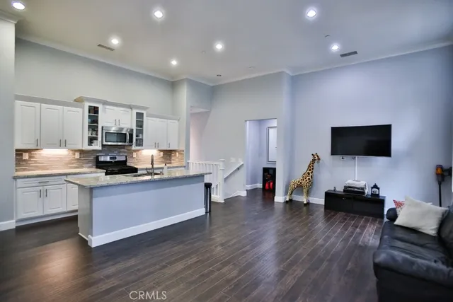 a living room with stainless steel appliances furniture and a flat screen tv