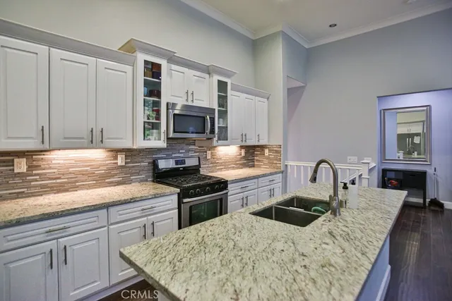 a kitchen with stainless steel appliances granite countertop a kitchen island a stove a sink dishwasher and cabinets with wooden floor