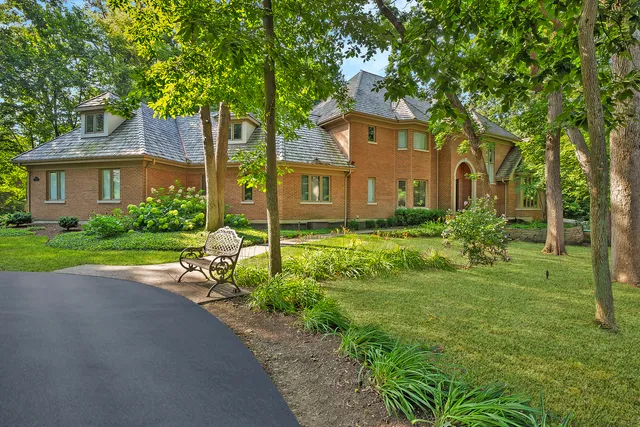 a view of a brick house with a big yard and large trees