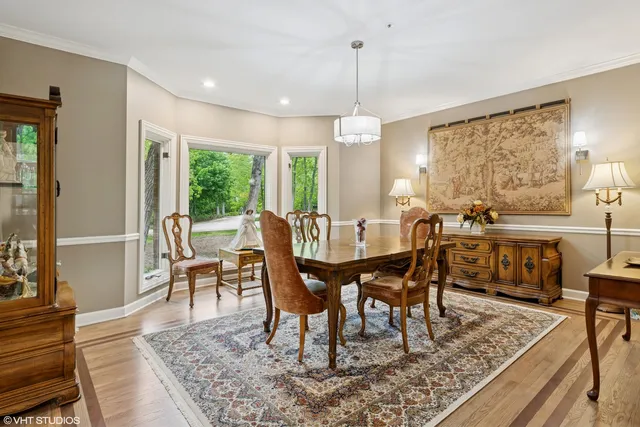 a view of a dining room and livingroom with furniture wooden floor a rug a fireplace and a chandelier