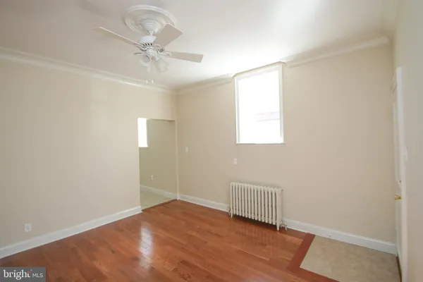 an empty room with wooden floor fan and windows