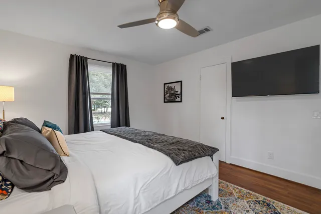 a bedroom with a large bed and a flat tv screen on dresser