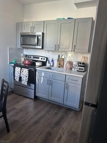 a kitchen with stainless steel appliances a stove a sink cabinets and a wooden floor