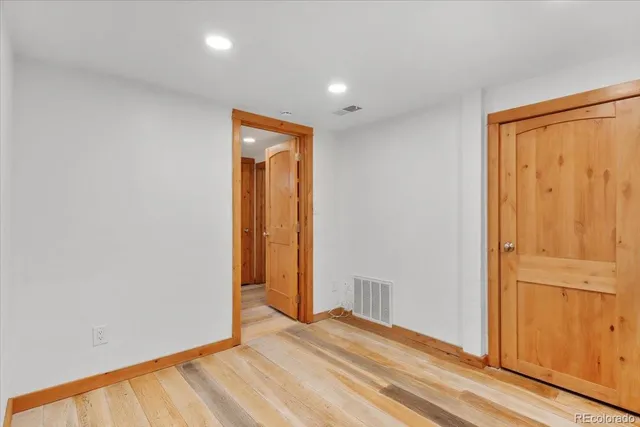 an empty room with wooden floor and closet area