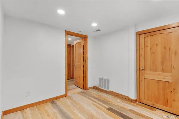 an empty room with wooden floor and closet area