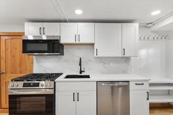 a kitchen with stainless steel appliances a stove a microwave and white cabinets