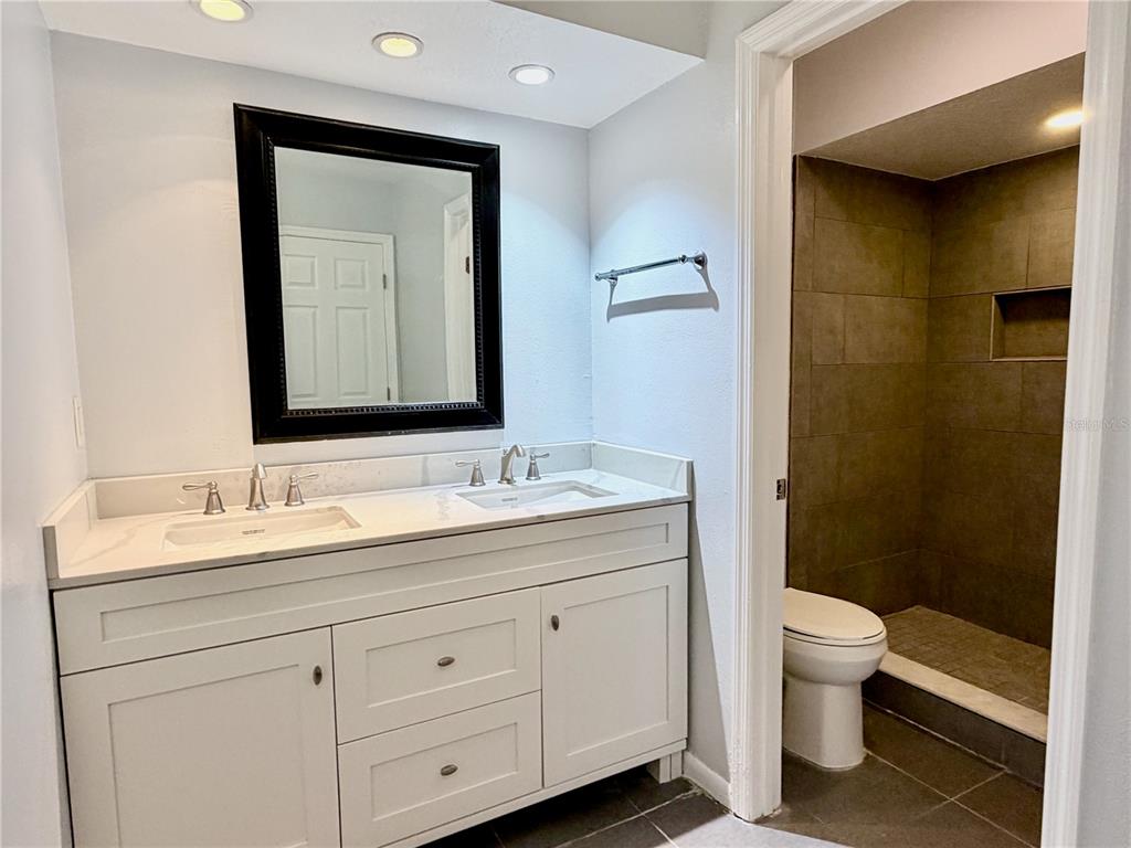 2284 Oak Neck Road, Unit F Clearwater, FL 33763 - Photo 30 of 34 a bathroom with a double vanity sink toilet and a mirror