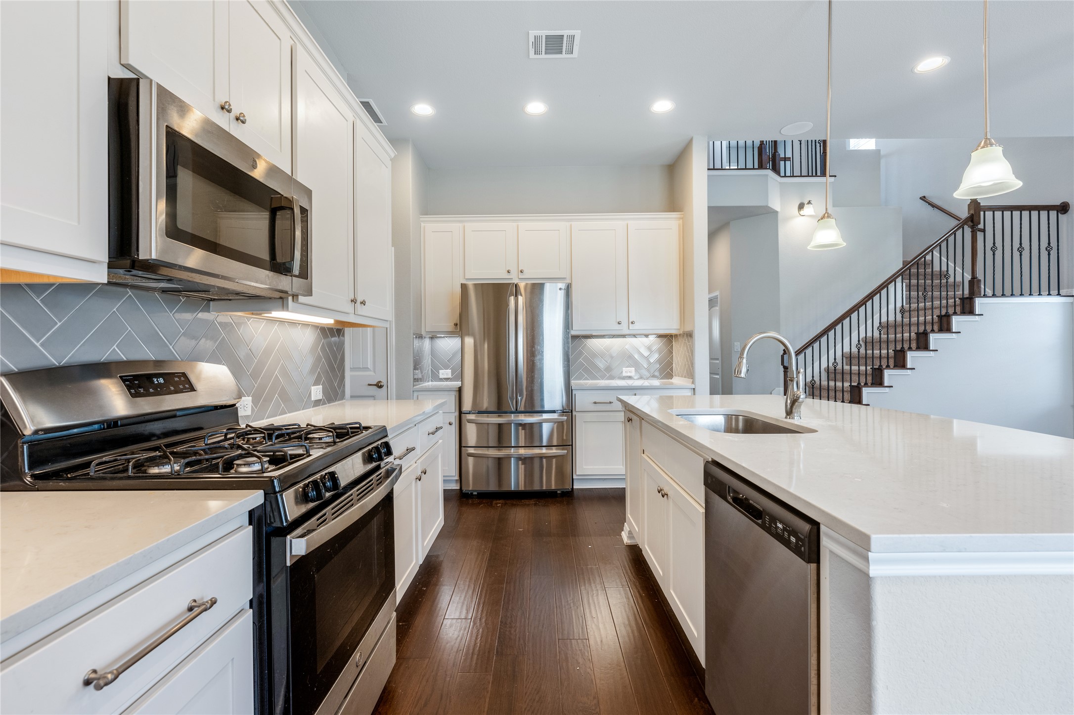 126 Rains Kyle, TX 78640 - Photo 15 of 22 Polished hardwood flooring and elegant quartz countertops anchor this modern open-concept kitchen.