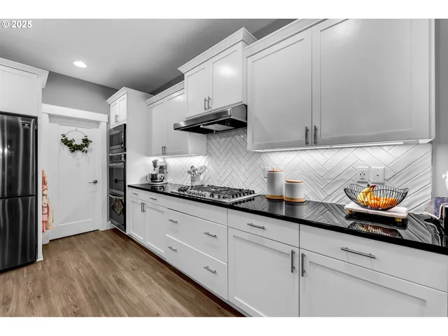 a kitchen with stainless steel appliances granite countertop a sink a stove and cabinets