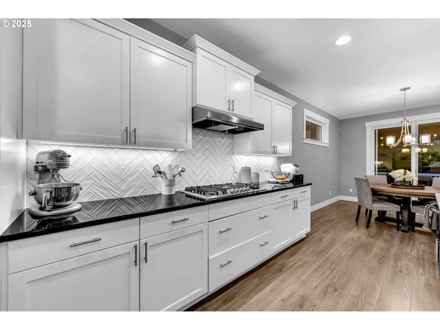 a kitchen with granite countertop lots of white cabinets and stainless steel appliances