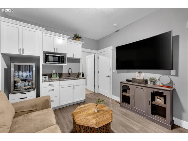 a living room with stainless steel appliances furniture and a flat screen tv