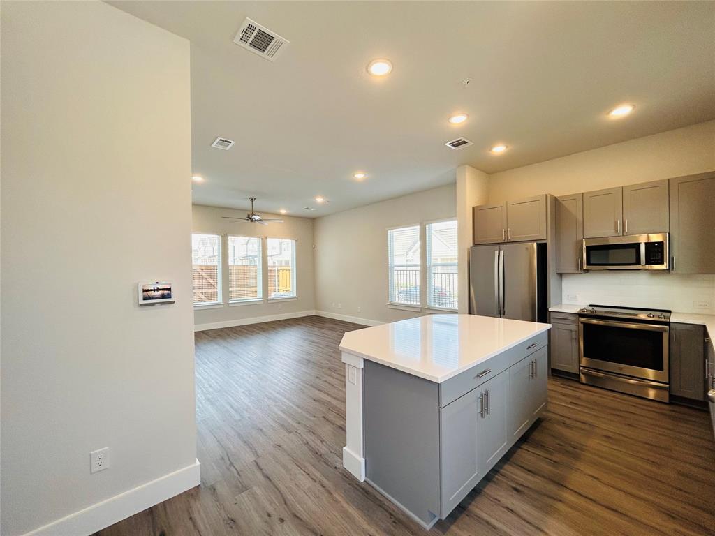 760 West Bedford Euless Road, Unit 214 Hurst, TX 76053 - Photo 19 of 32 a large kitchen with stainless steel appliances a large counter top a wooden floor and a window