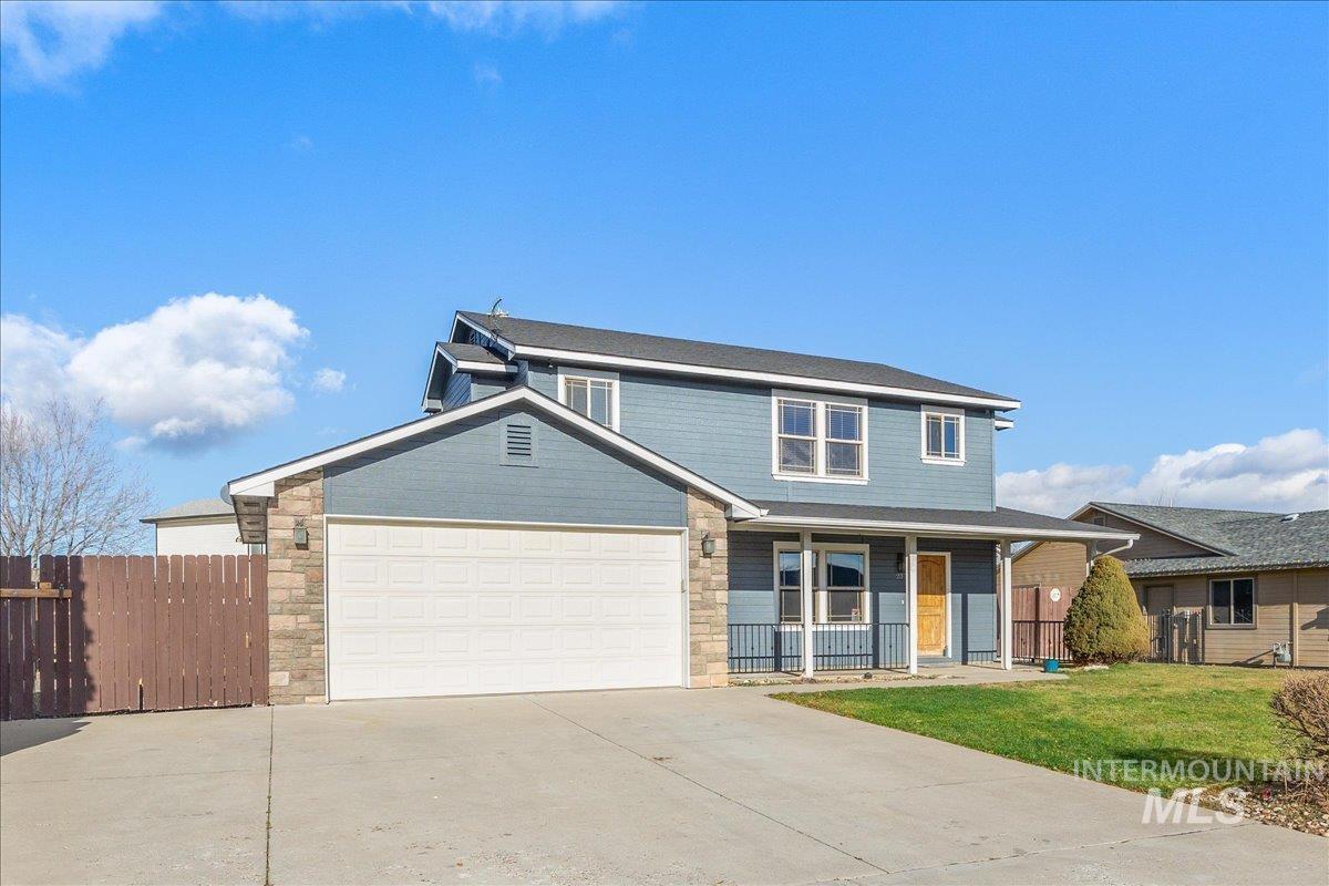 Traditional-style home with a porch, concrete driveway, an attached garage, and stone siding