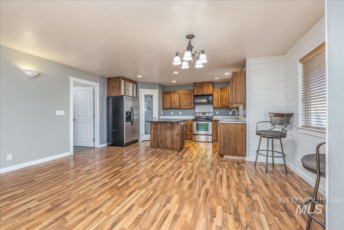 237 16th Avenue North Payette, ID 83661 - Photo 10 of 36 Kitchen with hanging light fixtures, a chandelier, brown cabinetry, appliances with stainless steel finishes, and a center island