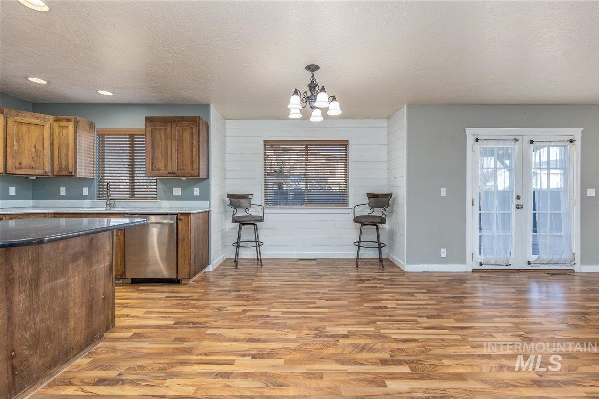 237 16th Avenue North Payette, ID 83661 - Photo 11 of 36 Kitchen featuring a textured ceiling, pendant lighting, brown cabinetry, light wood-style flooring, and dishwasher