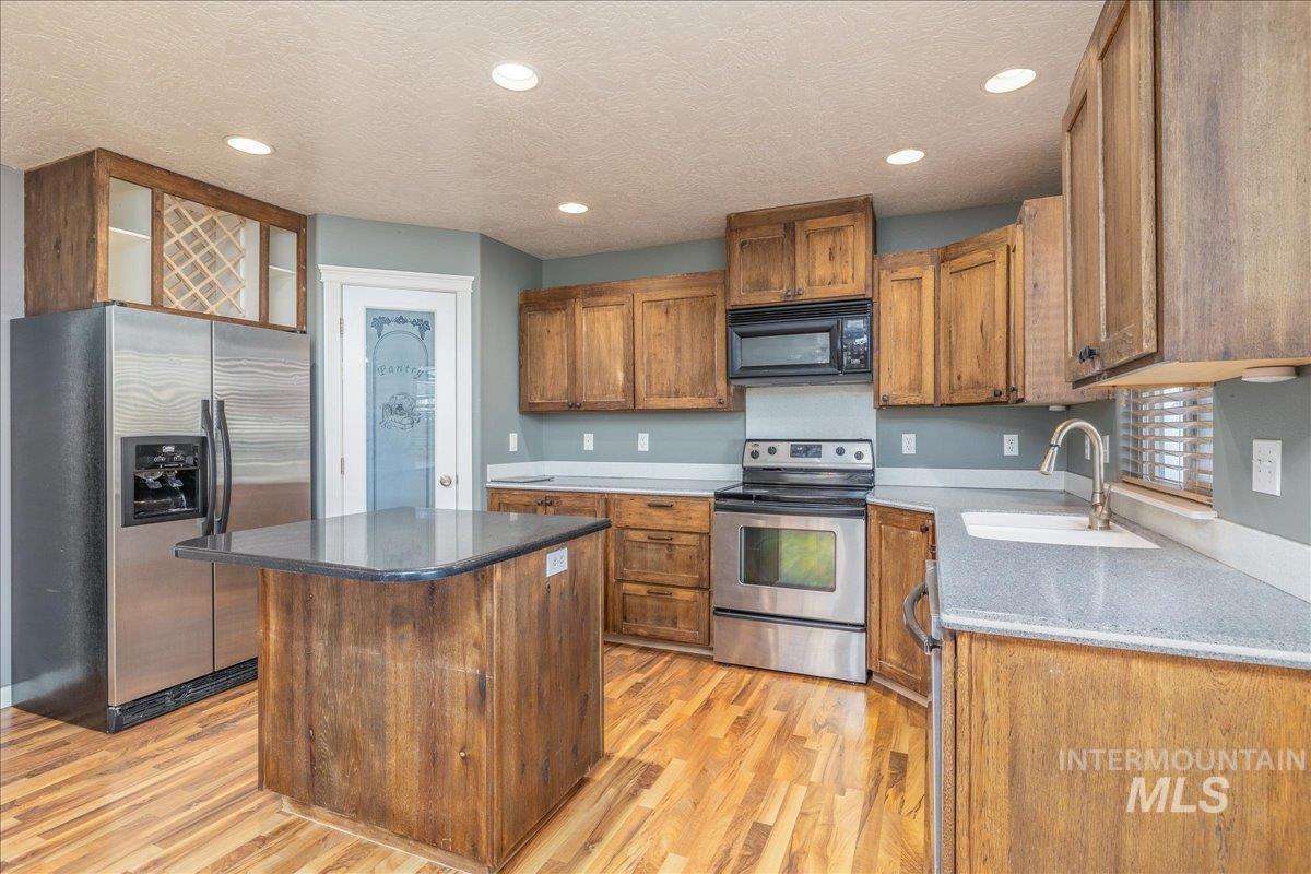 237 16th Avenue North Payette, ID 83661 - Photo 13 of 36 Kitchen with appliances with stainless steel finishes, brown cabinetry, a center island, light wood-style floors, and recessed lighting
