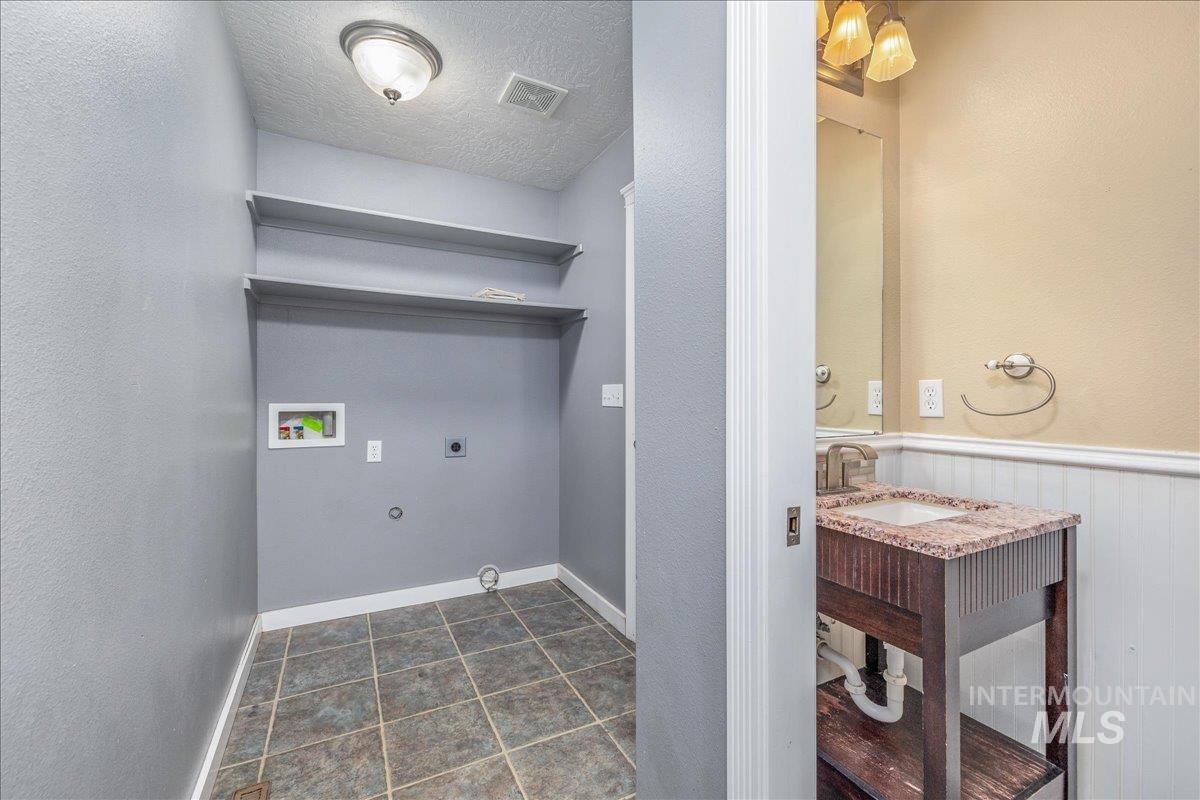 237 16th Avenue North Payette, ID 83661 - Photo 15 of 36 Washroom with a textured ceiling, washer hookup, a wainscoted wall, dark tile patterned flooring, and a textured wall