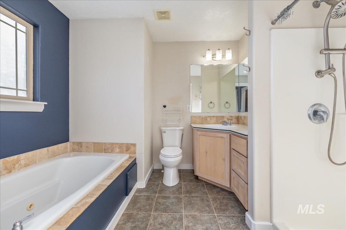 237 16th Avenue North Payette, ID 83661 - Photo 23 of 36 Full bath with vanity, a bath, a shower, and dark tile patterned floors