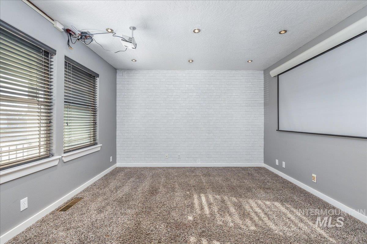 237 16th Avenue North Payette, ID 83661 - Photo 7 of 36 Home theater room featuring brick wall, a textured ceiling, carpet flooring, and an accent wall