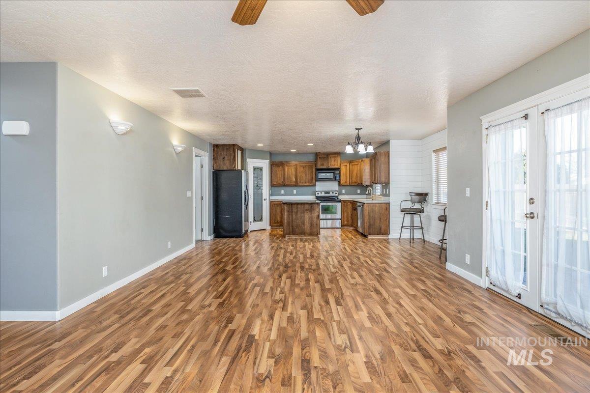 237 16th Avenue North Payette, ID 83661 - Photo 36 of 36 Kitchen featuring open floor plan, brown cabinetry, ceiling fan, appliances with stainless steel finishes, and light countertops