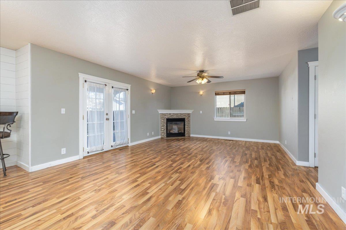 237 16th Avenue North Payette, ID 83661 - Photo 9 of 36 Unfurnished living room featuring a textured ceiling, light wood-style floors, a fireplace, and ceiling fan