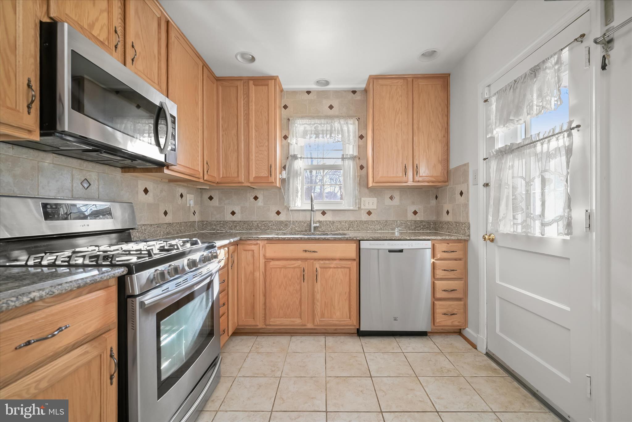 3637 Sussex Road Pikesville, MD 21207 - Photo 17 of 33 a kitchen with stainless steel appliances granite countertop a stove a sink and a microwave