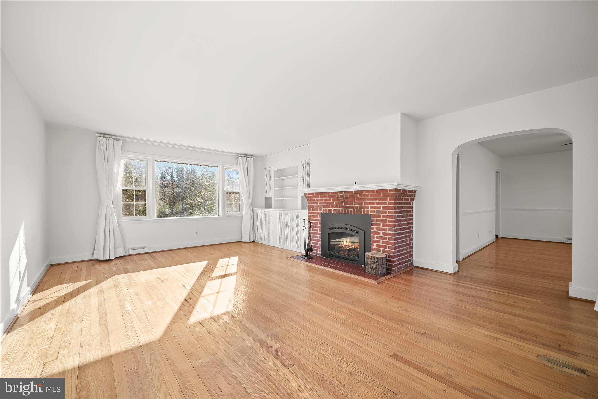 3637 Sussex Road Pikesville, MD 21207 - Photo 9 of 33 an empty room with wooden floor fireplace and windows