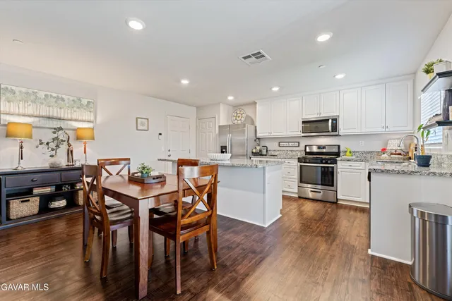 a kitchen with stainless steel appliances granite countertop a stove a sink a microwave a dining table and chairs