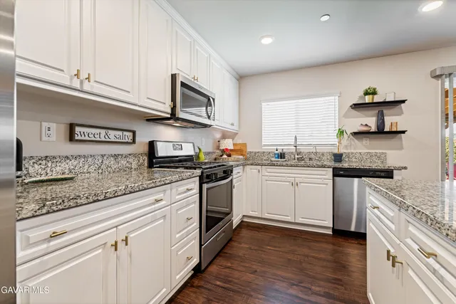 a kitchen with granite countertop white cabinets and white appliances