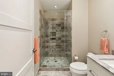 a bathroom with a granite countertop bathtub shower sink mirror and toilet