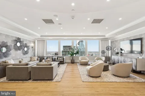 a living room with furniture kitchen view and large windows