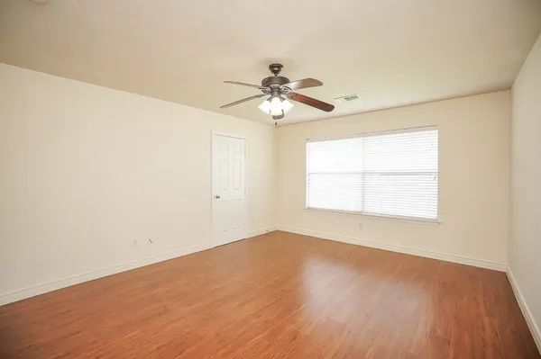 an empty room with a window and a ceiling fan