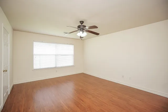 an empty room with a window and a ceiling fan