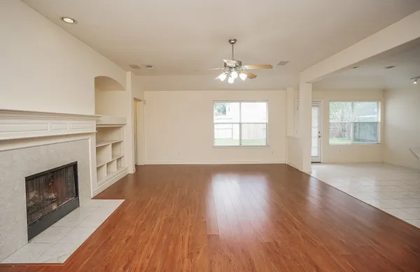 an empty room with wooden floor fireplace and windows
