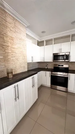 a kitchen with granite countertop white cabinets and white appliances