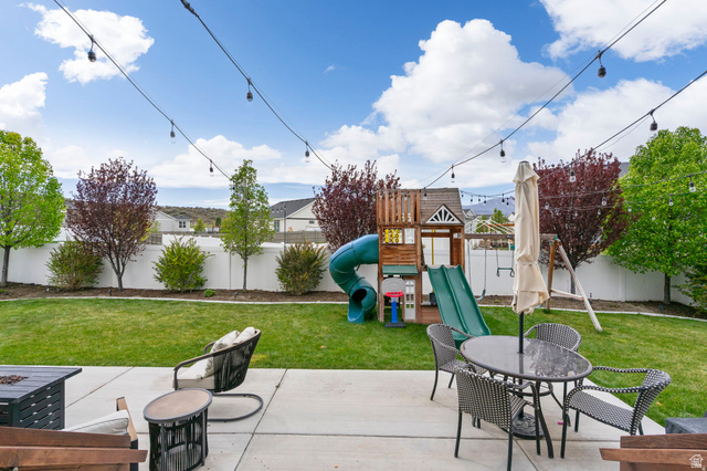 7685 Timber Country Road Eagle Mountain, UT 84005 - Photo 30 of 39 Expansive backyard featuring a concrete patio, string lighting, manicured lawn, and a white perimeter fence