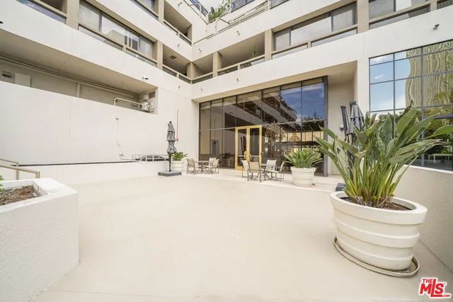 a patio with a table and chairs and potted plants