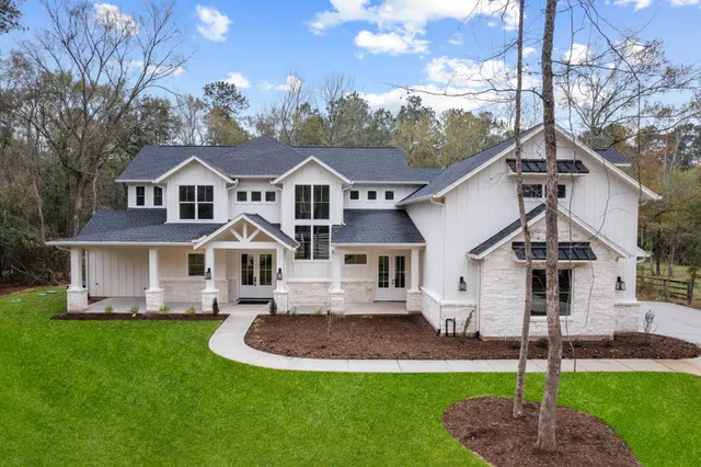 a front view of a house with a garden and trees